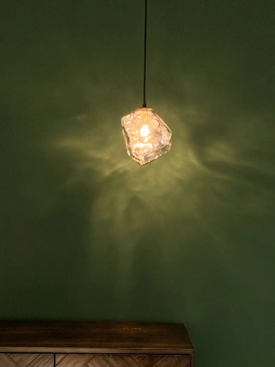 Minimalist ice cube glass chandelier with warm 4000K light, smoky grey shade and black hanging wire over a dining table