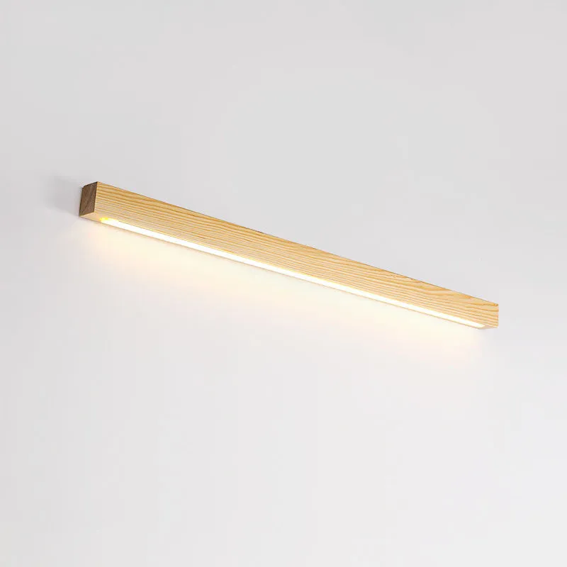Slim, long walnut-coloured wooden strip wall lamp mounted on a plain wall.