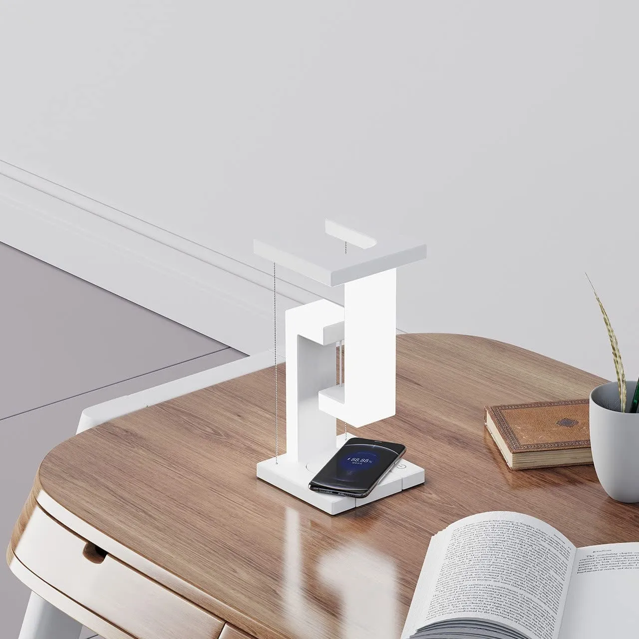 White magnetic suspension table lamp with wireless charging base, floating shade, and foldable bracket on a desk