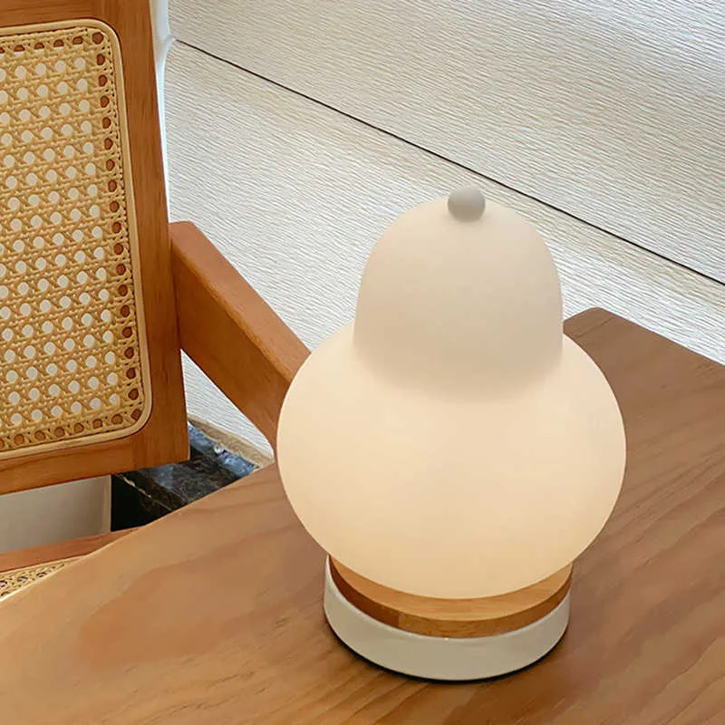 White pear-shaped rechargeable touch LED table lamp with PE shade on a wooden bedside table
