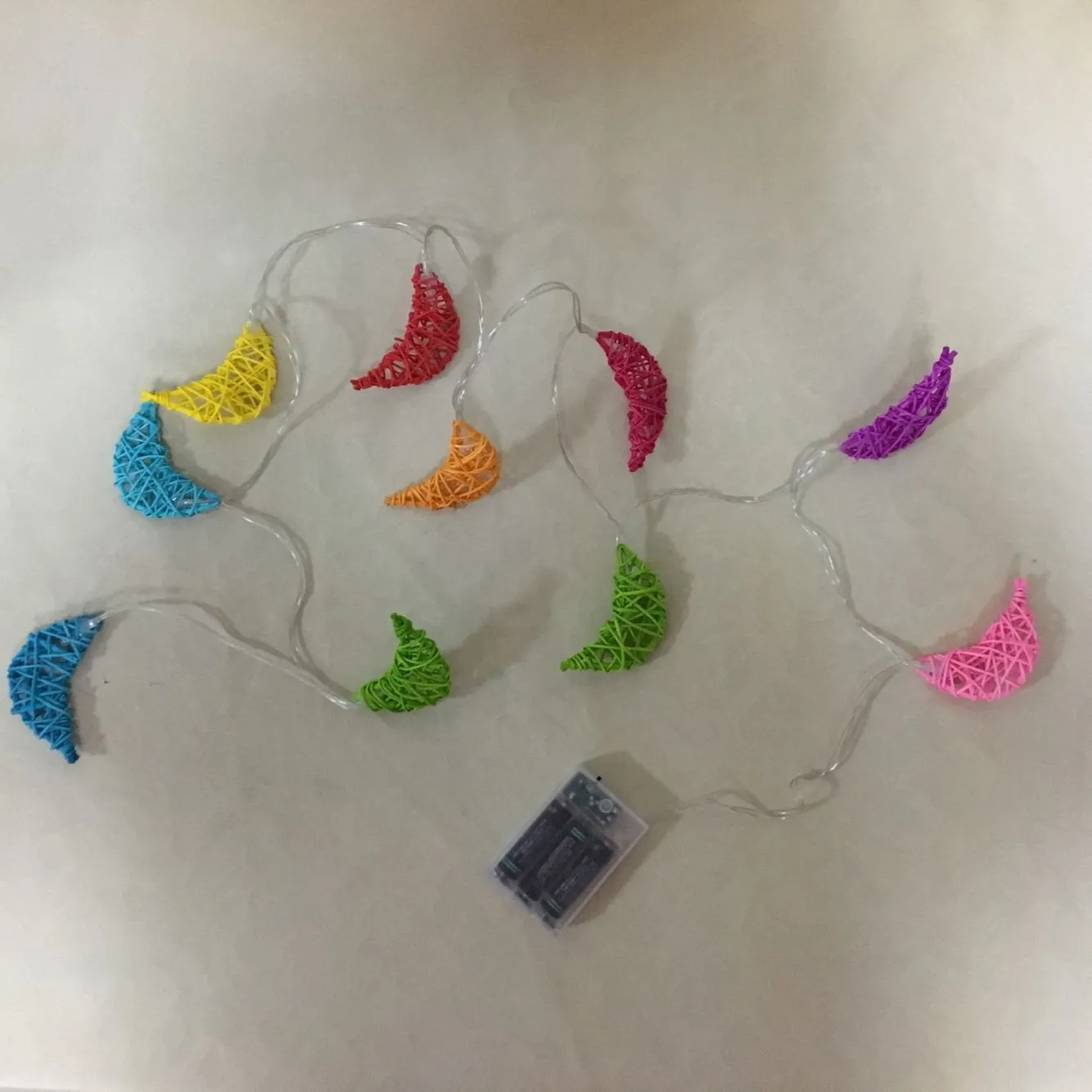 Handwoven rattan moon pendant fairy light chain with warm white glow on a dark background