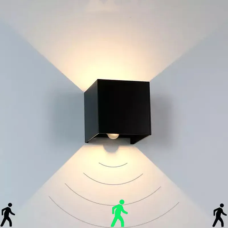 Black aluminium square wall lamp mounted on a corridor wall, showing 100mm size and 360-degree light emission.