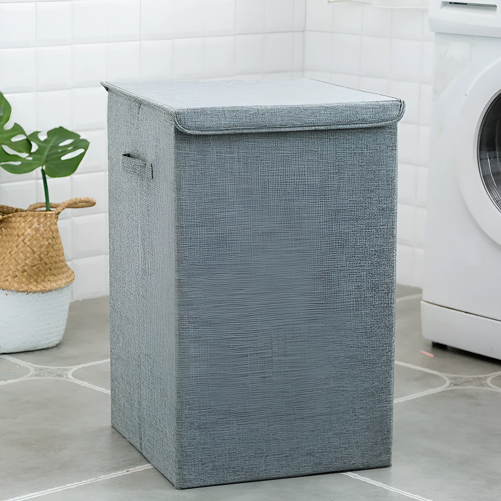 Washable fabric laundry sorting box in beige, shown next to a small pile of towels.