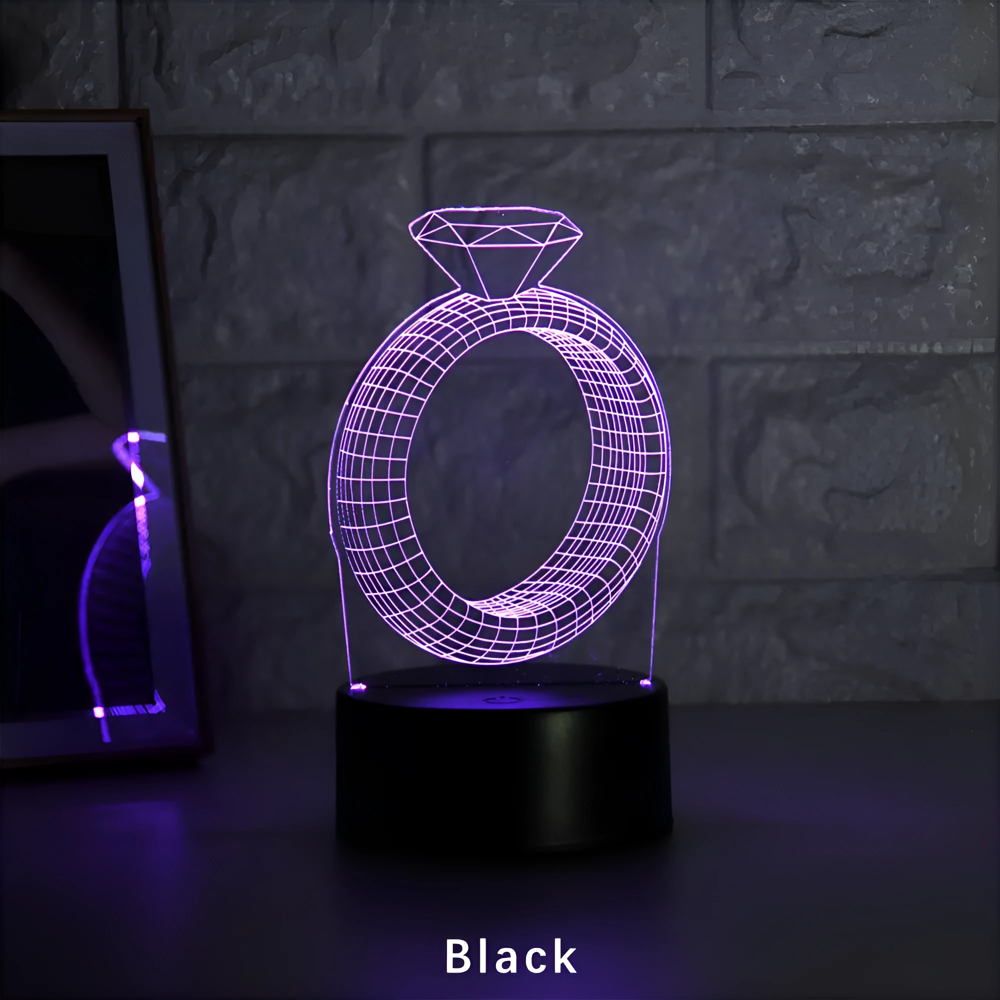 3D holographic diamond ring LED night light with colour changing modes on a bedside table.