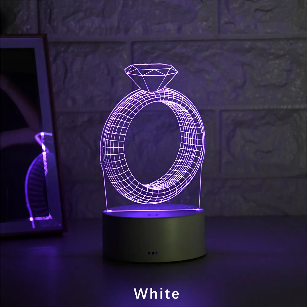 3D holographic diamond ring LED night light with colour changing modes on a bedside table.