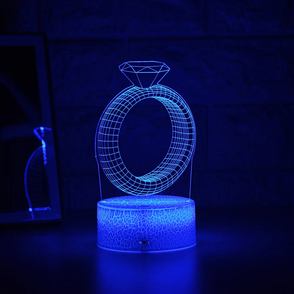 3D holographic diamond ring LED night light with colour changing modes on a bedside table.