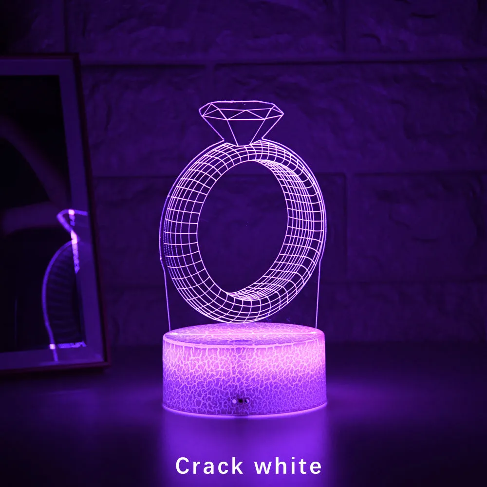 3D holographic diamond ring LED night light with colour changing modes on a bedside table.