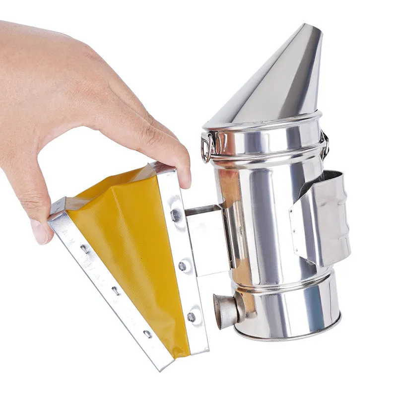 Portable stainless steel beekeeping smoker with leather bellows on a wooden surface