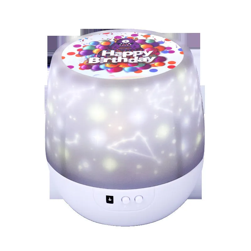 Compact white starry sky projector lamp with film discs on a table, projecting galaxy scene on wall.