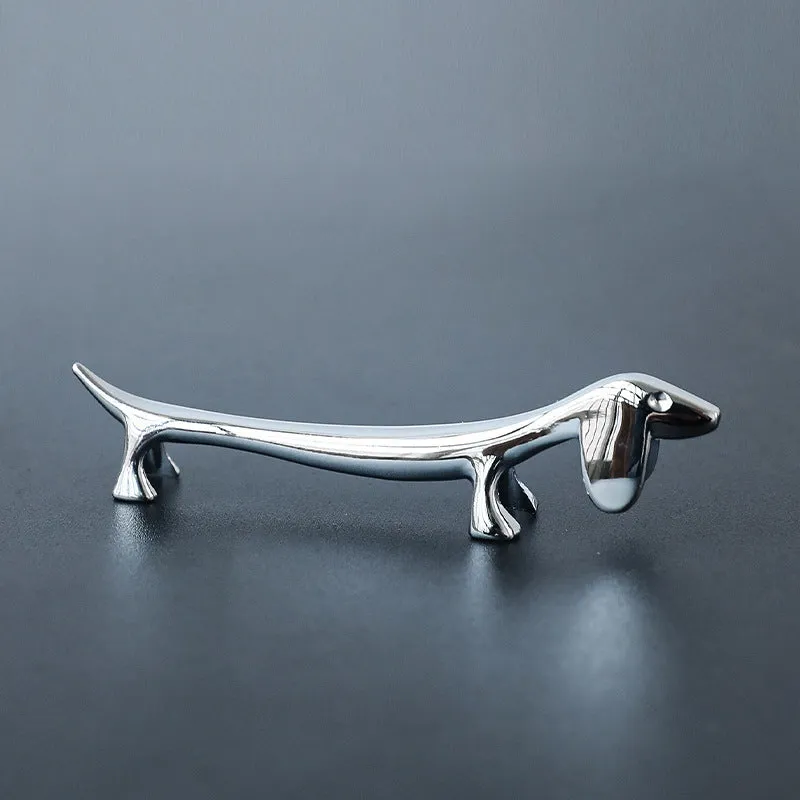 Silver zinc alloy sausage dog chopstick rest knife holder on desk with pen and chopsticks