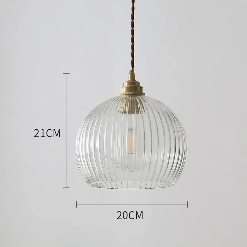 Minimal single head pendant lamp with copper body and transparent glass shade on a dark background