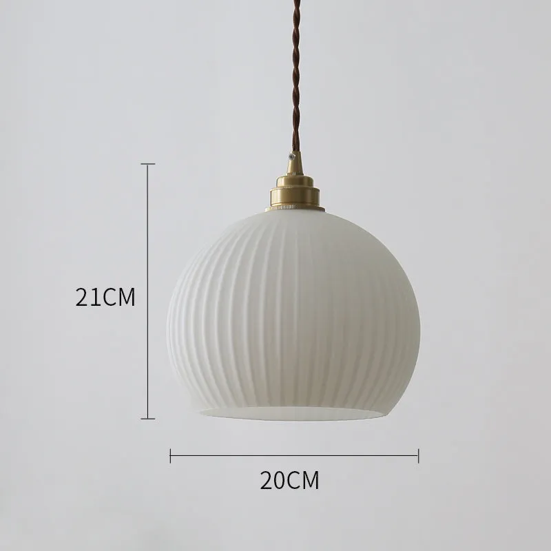 Minimal single head pendant lamp with copper body and transparent glass shade on a dark background