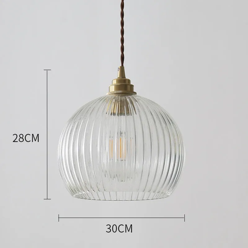 Minimal single head pendant lamp with copper body and transparent glass shade on a dark background
