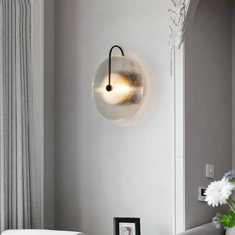 Round glass wall lamp in gold finish mounted on a wall with iron body and clear glass lampshade