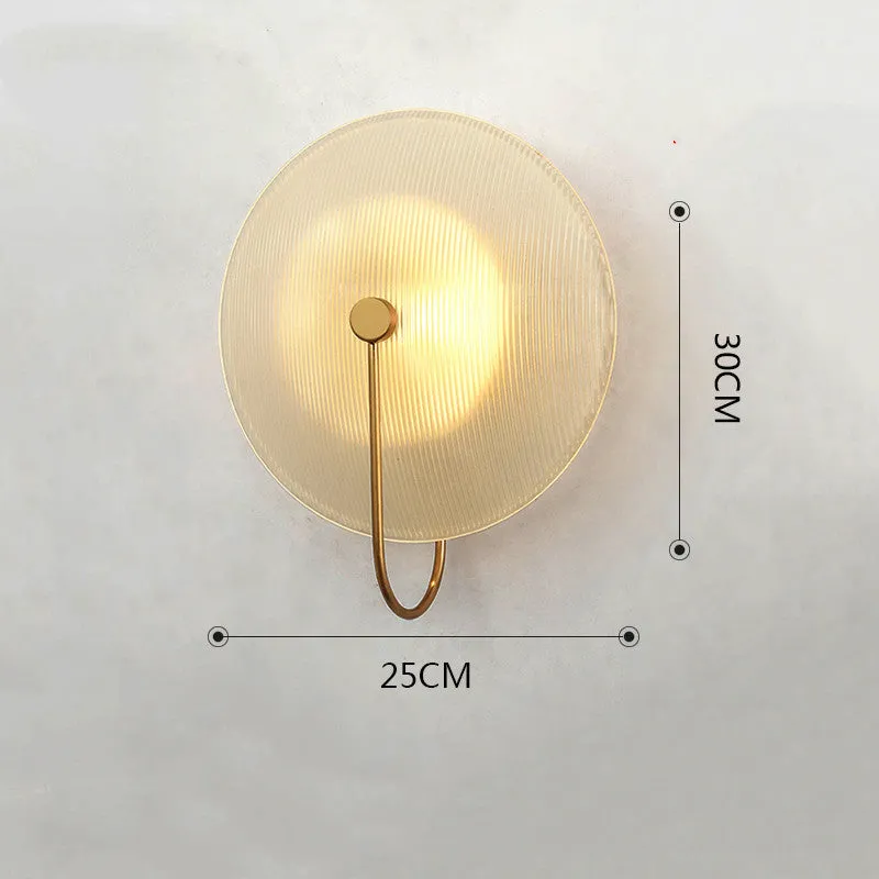 Round glass wall lamp in gold finish mounted on a wall with iron body and clear glass lampshade