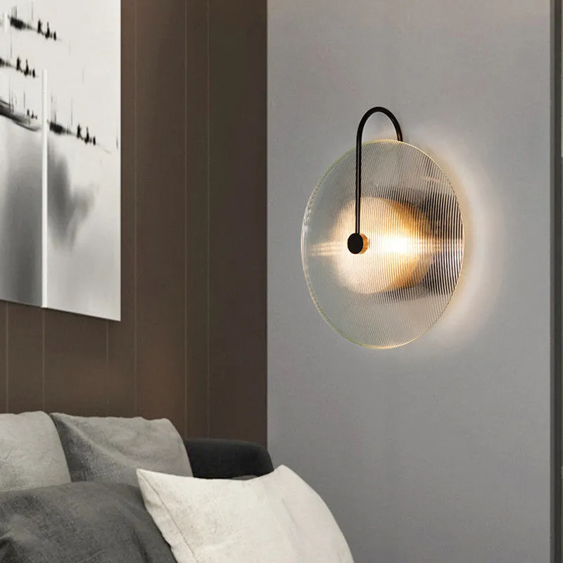 Round glass wall lamp in gold finish mounted on a wall with iron body and clear glass lampshade