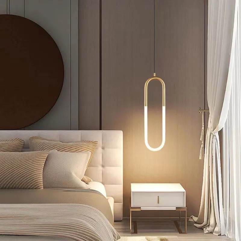 Modern Nordic-style U-shaped metal pendant light with a long black cable, hung above a bedside table.