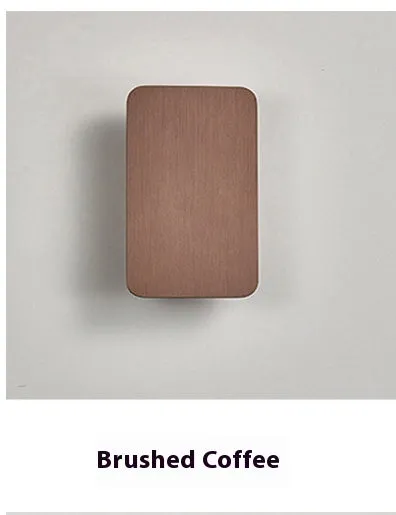 Minimalist black nordic wall lamp mounted beside a bed, emitting warm white light.