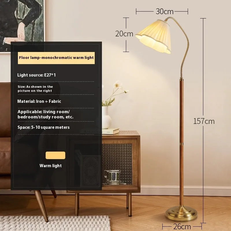Solid wood floor lamp with fabric shade in walnut colour placed beside a sofa in a living room