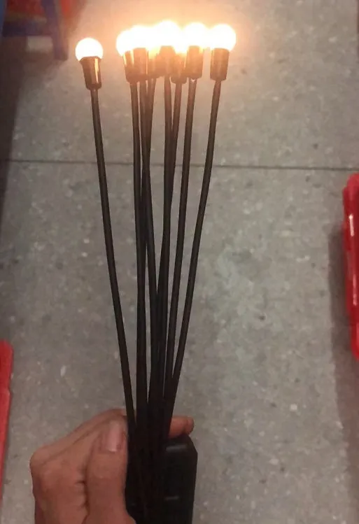 Solar-powered LED firefly garden spike light with multiple heads and a press-in ground plug on grass.