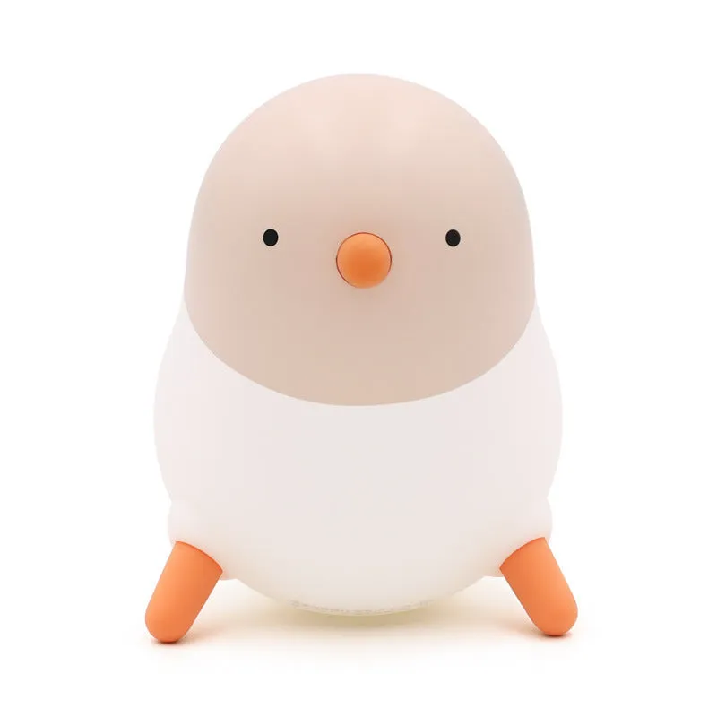 Pecking rice chicken small night light with warm yellow glow on a wooden bedside table, USB charging cable visible