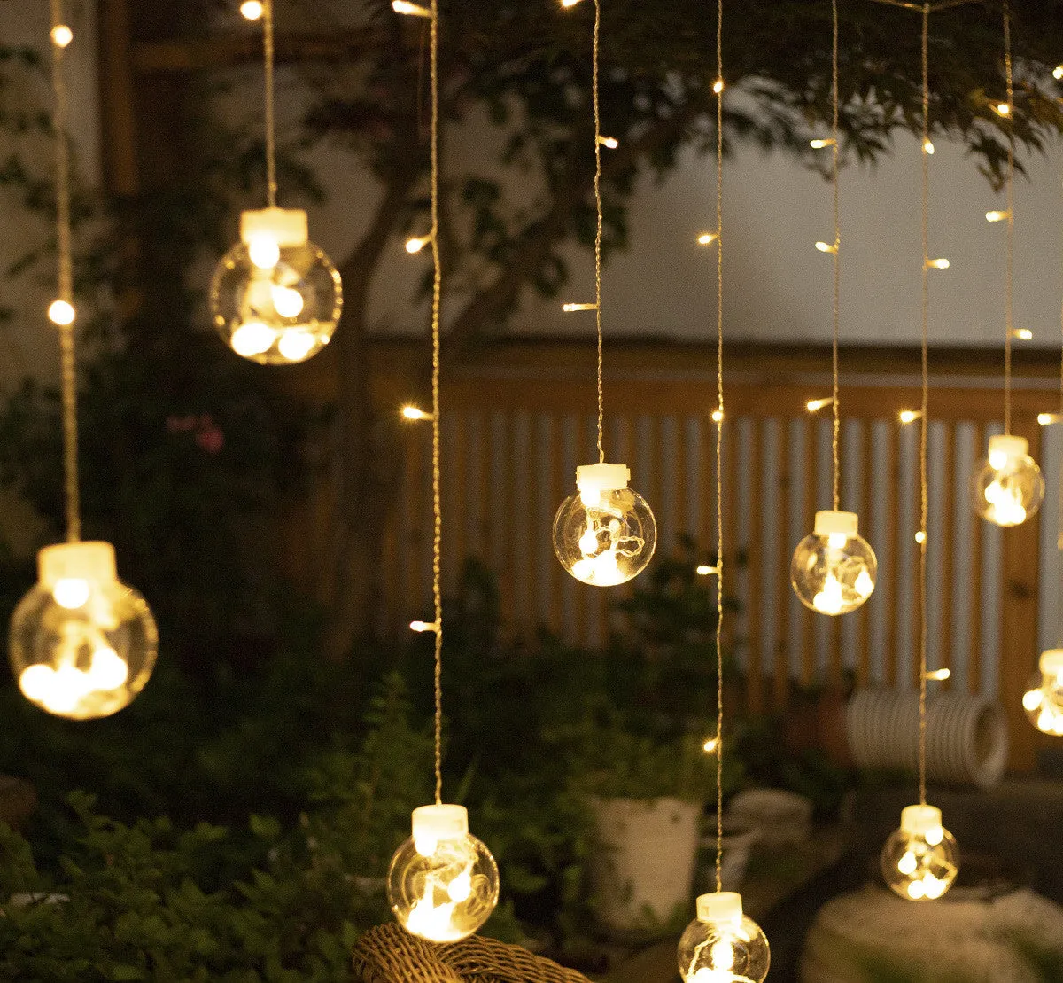 2.5 metre 108 LED curtain light string in warm white mode on a dark background showing plastic shell and plug-in cable