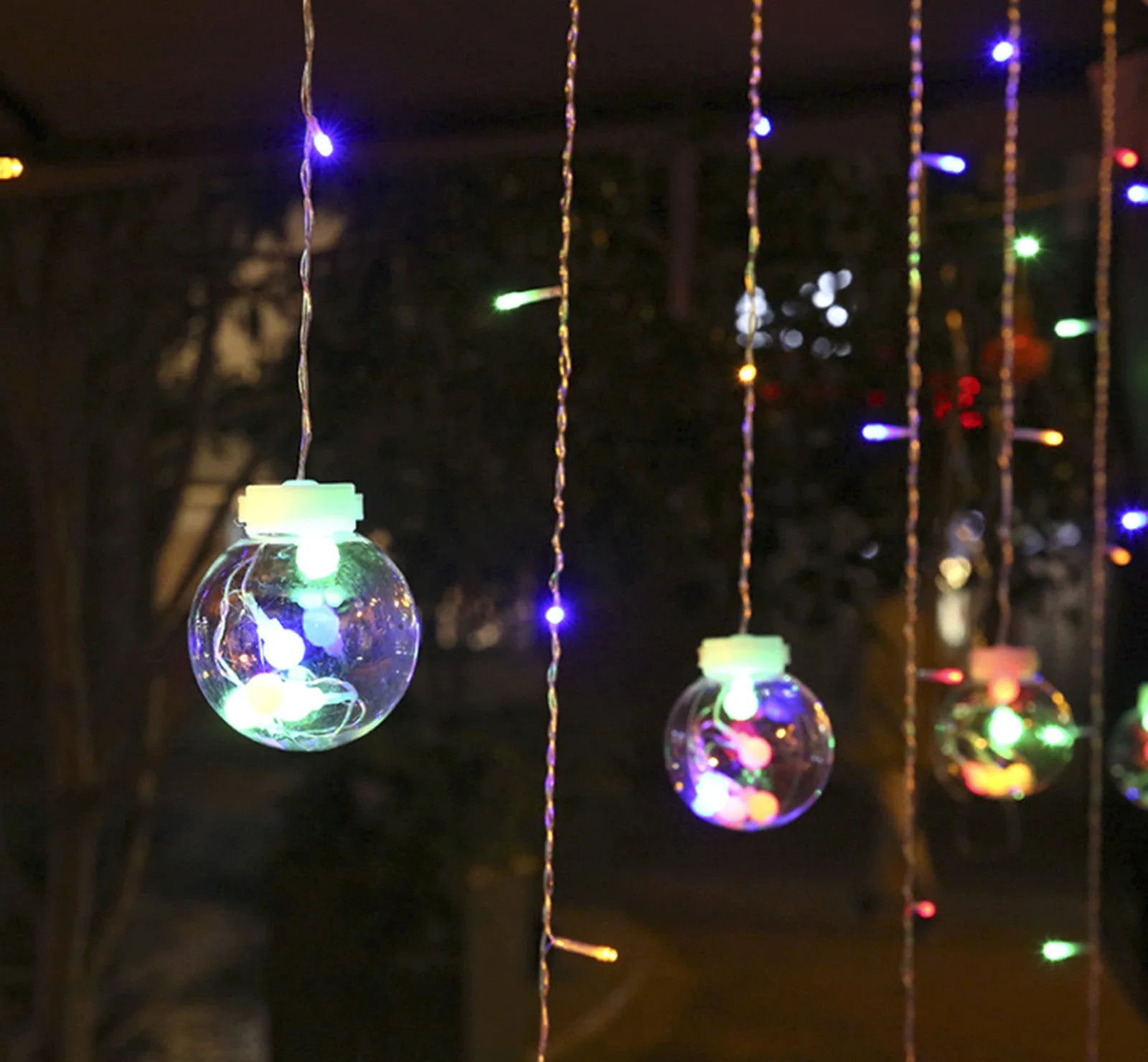 2.5 metre 108 LED curtain light string in warm white mode on a dark background showing plastic shell and plug-in cable