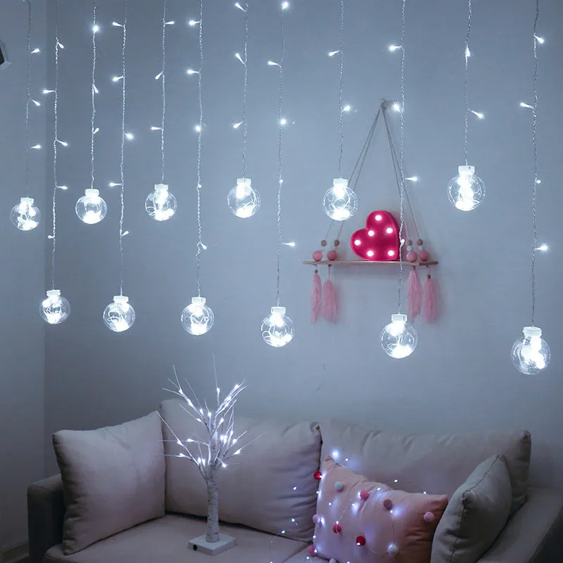 2.5 metre 108 LED curtain light string in warm white mode on a dark background showing plastic shell and plug-in cable