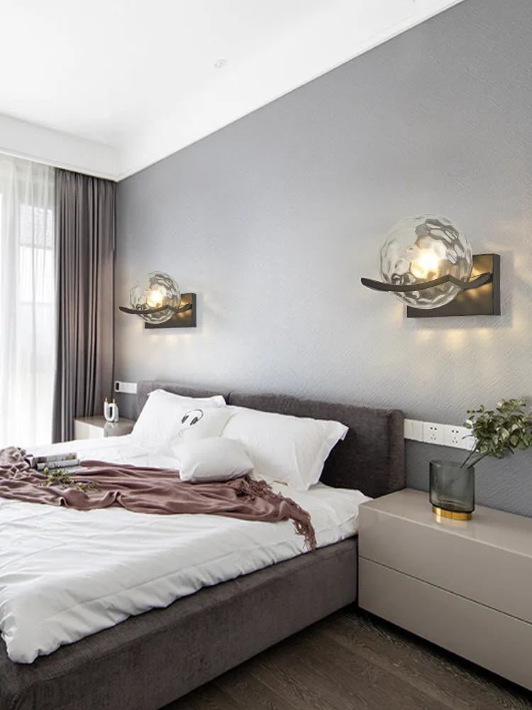 Modern minimalist black wall lamp with striped clear cover mounted beside a bed