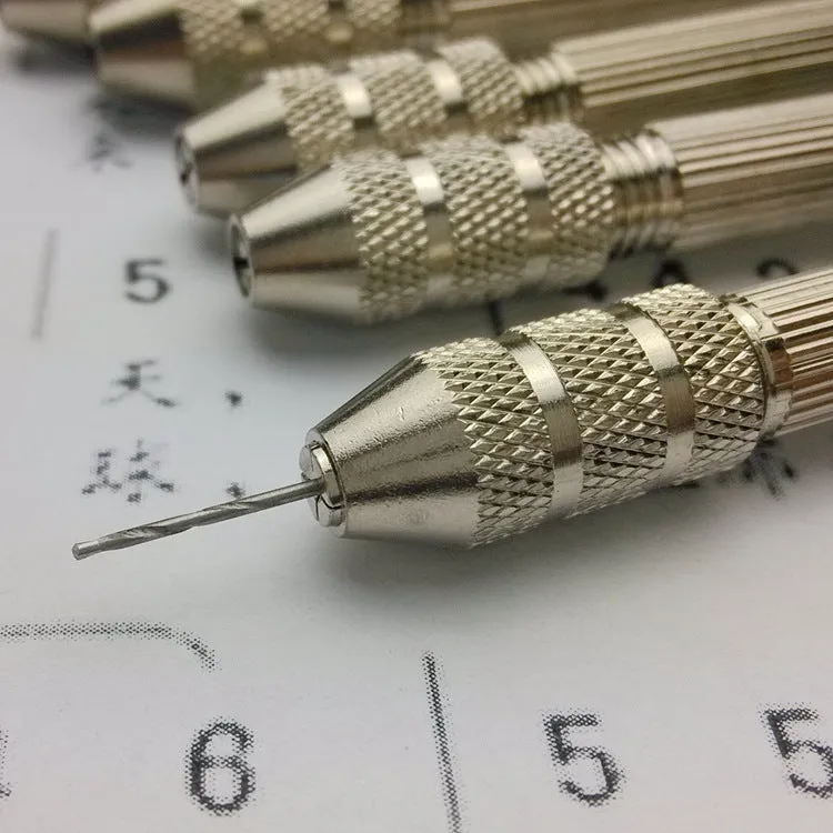 Hand twist drill with two collets and four drill bits on a wooden surface