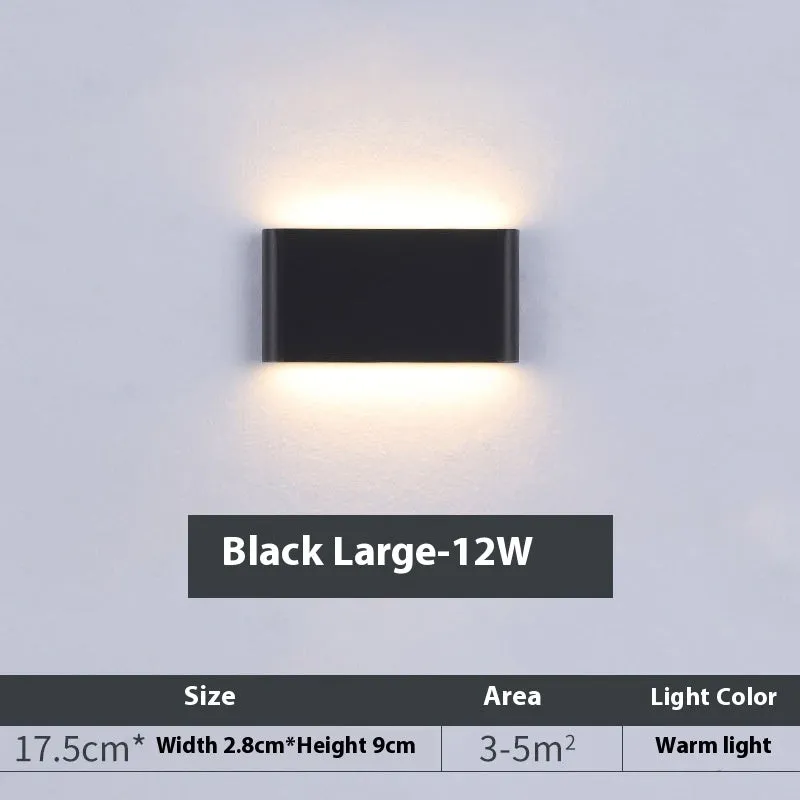 Rectangular LED outdoor wall lamp in black finish with warm light on a brick courtyard wall
