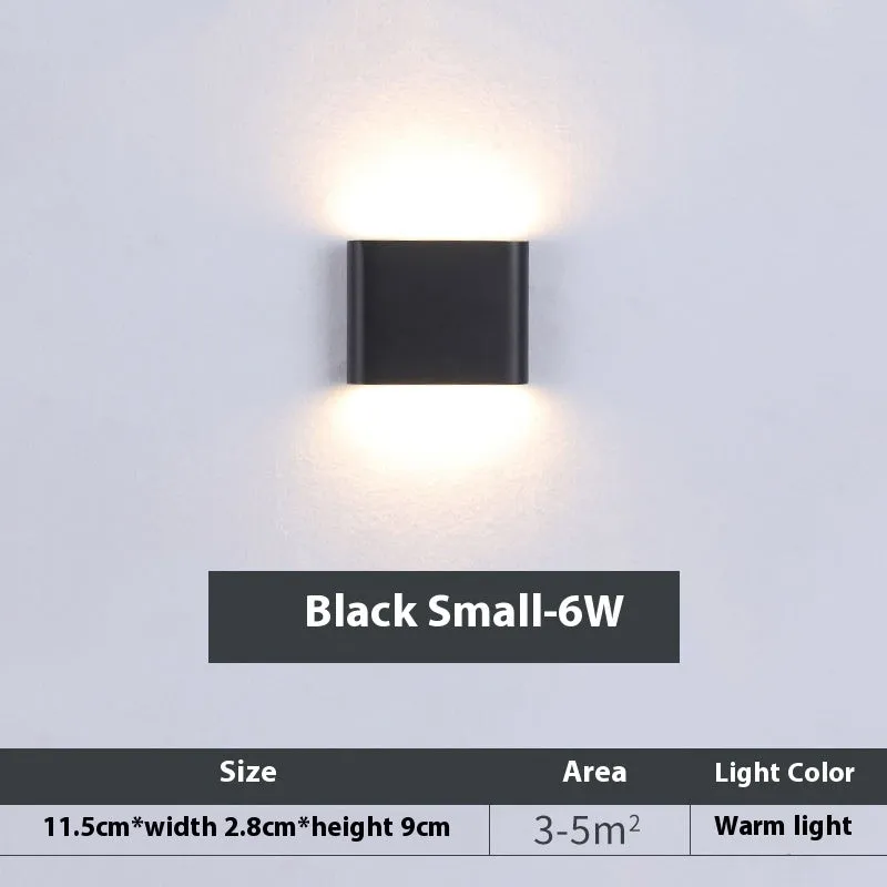 Rectangular LED outdoor wall lamp in black finish with warm light on a brick courtyard wall