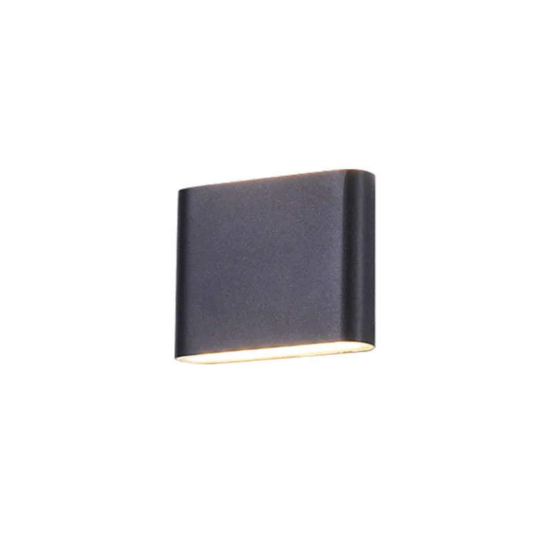 Rectangular LED outdoor wall lamp in black finish with warm light on a brick courtyard wall