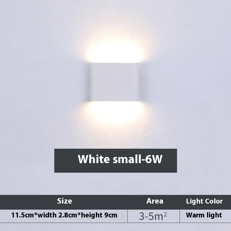 Rectangular LED outdoor wall lamp in black finish with warm light on a brick courtyard wall