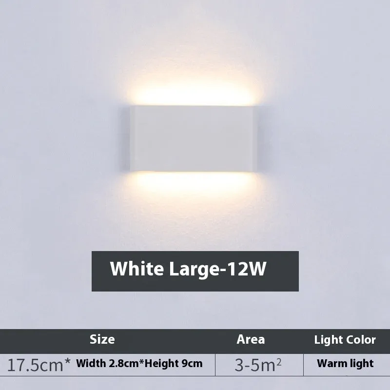 Rectangular LED outdoor wall lamp in black finish with warm light on a brick courtyard wall