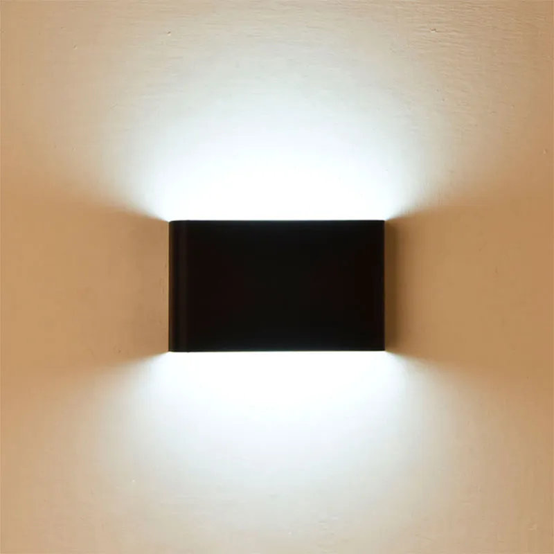 Rectangular LED outdoor wall lamp in black finish with warm light on a brick courtyard wall