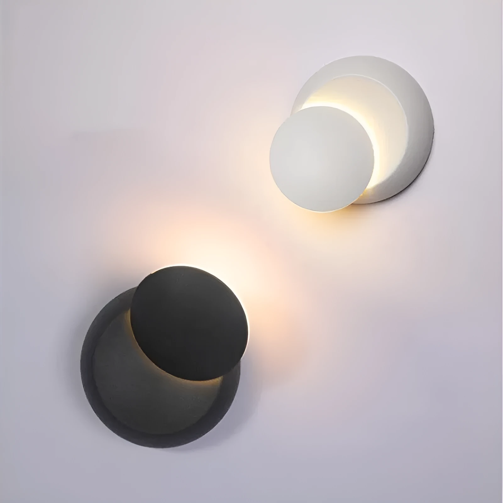 Rotating lunar eclipse LED wall lamp with aluminium shade in black finish on a living room wall