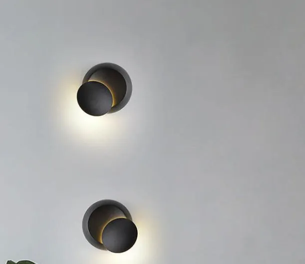 Rotating lunar eclipse LED wall lamp with aluminium shade in black finish on a living room wall