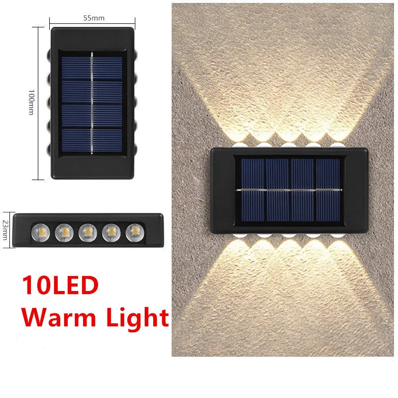 Black solar outdoor garden wall light with up and down glowing effect on a brick wall at night