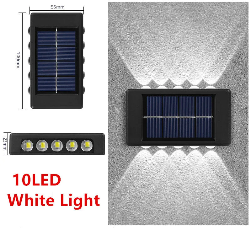 Black solar outdoor garden wall light with up and down glowing effect on a brick wall at night
