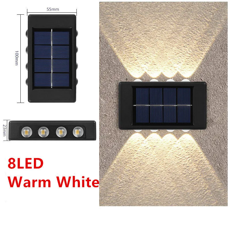 Black solar outdoor garden wall light with up and down glowing effect on a brick wall at night
