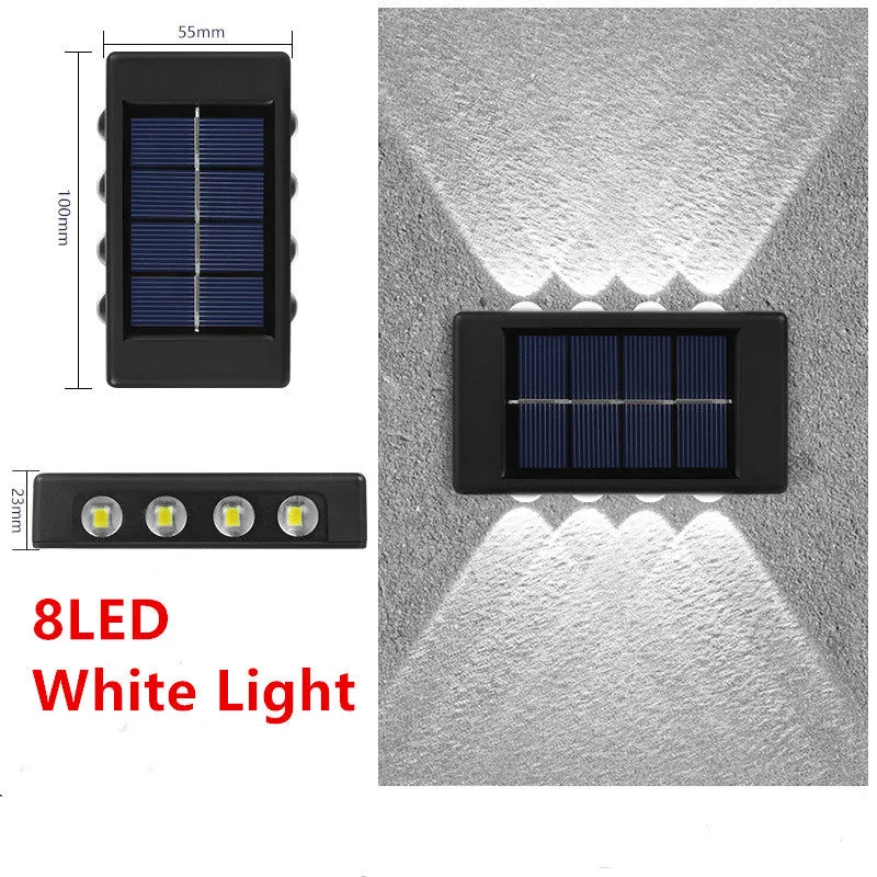 Black solar outdoor garden wall light with up and down glowing effect on a brick wall at night