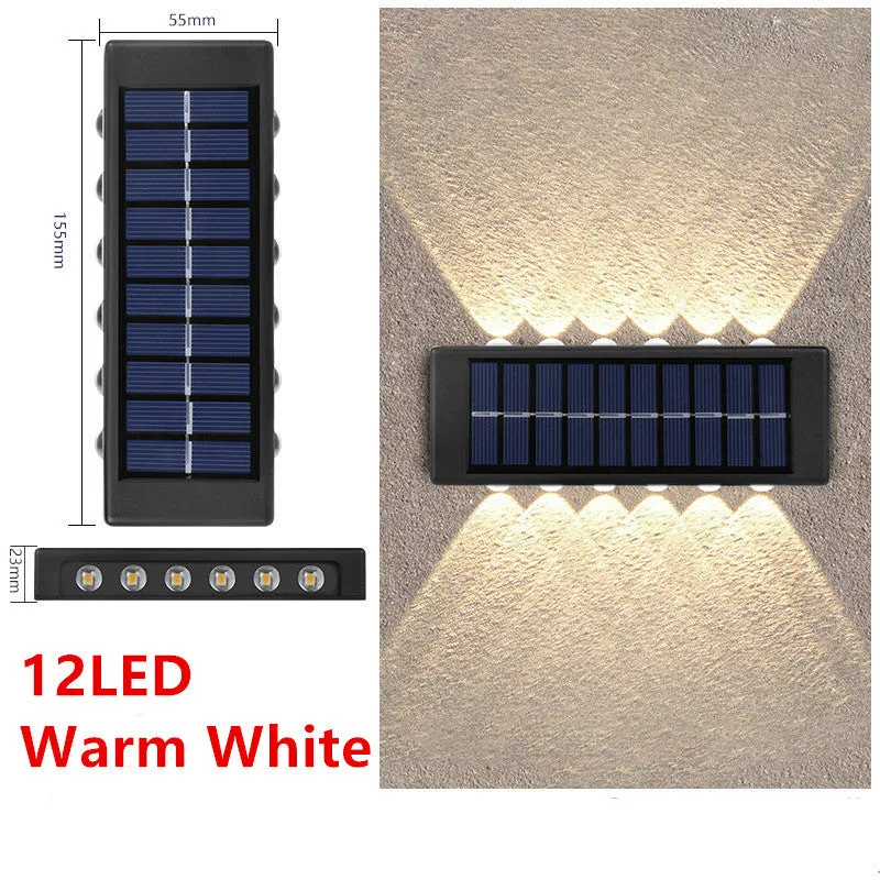Black solar outdoor garden wall light with up and down glowing effect on a brick wall at night