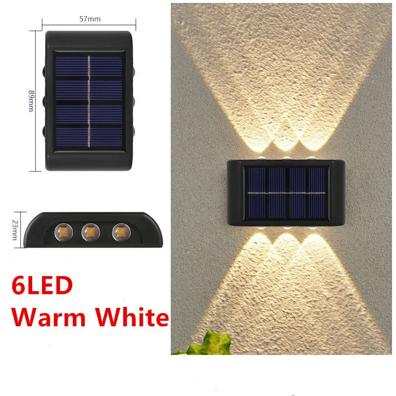 Black solar outdoor garden wall light with up and down glowing effect on a brick wall at night