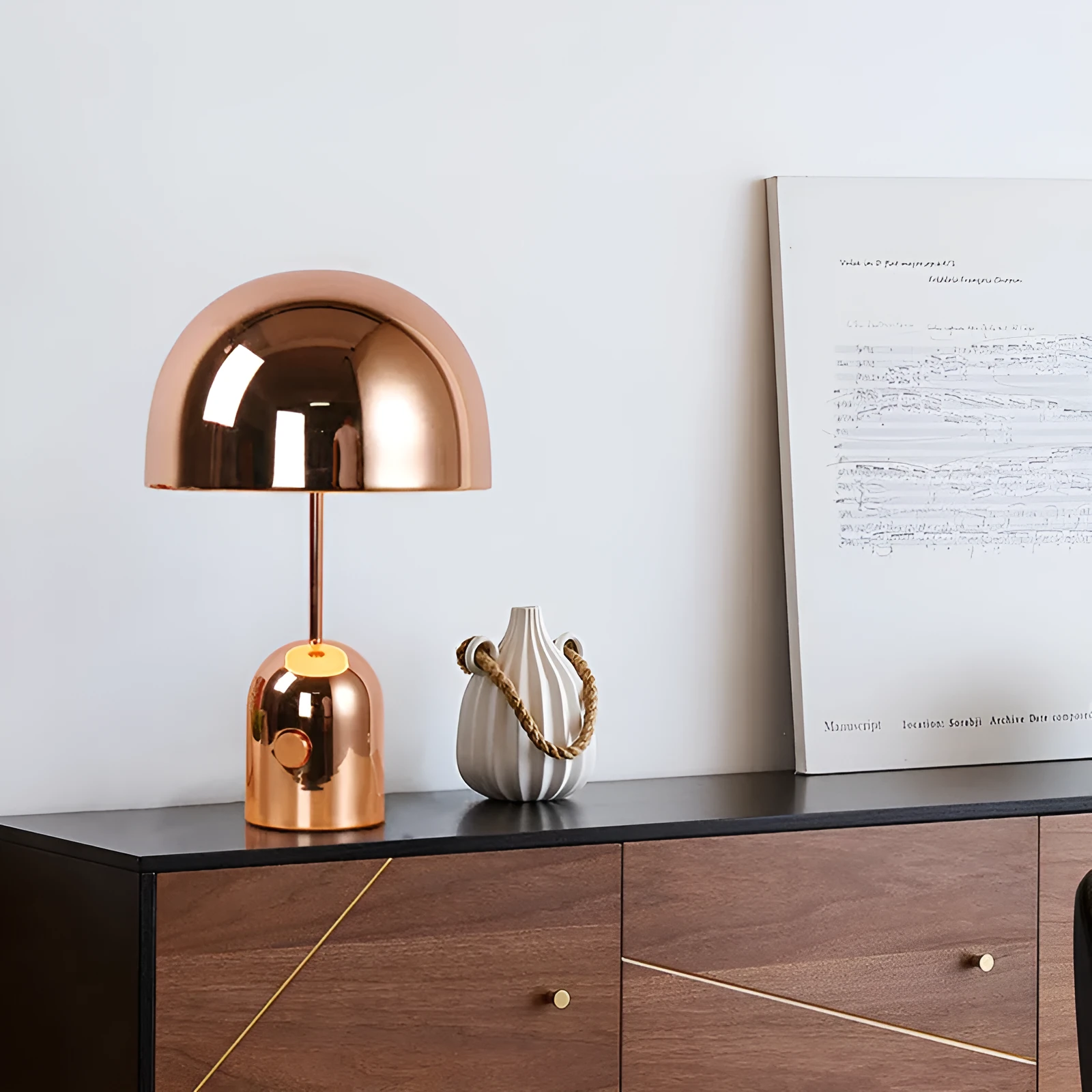 Modern mushroom table lamp with metal base in rose gold finish on a wooden table.