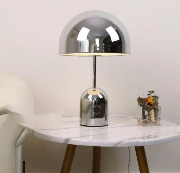 Modern mushroom table lamp with metal base in rose gold finish on a wooden table.