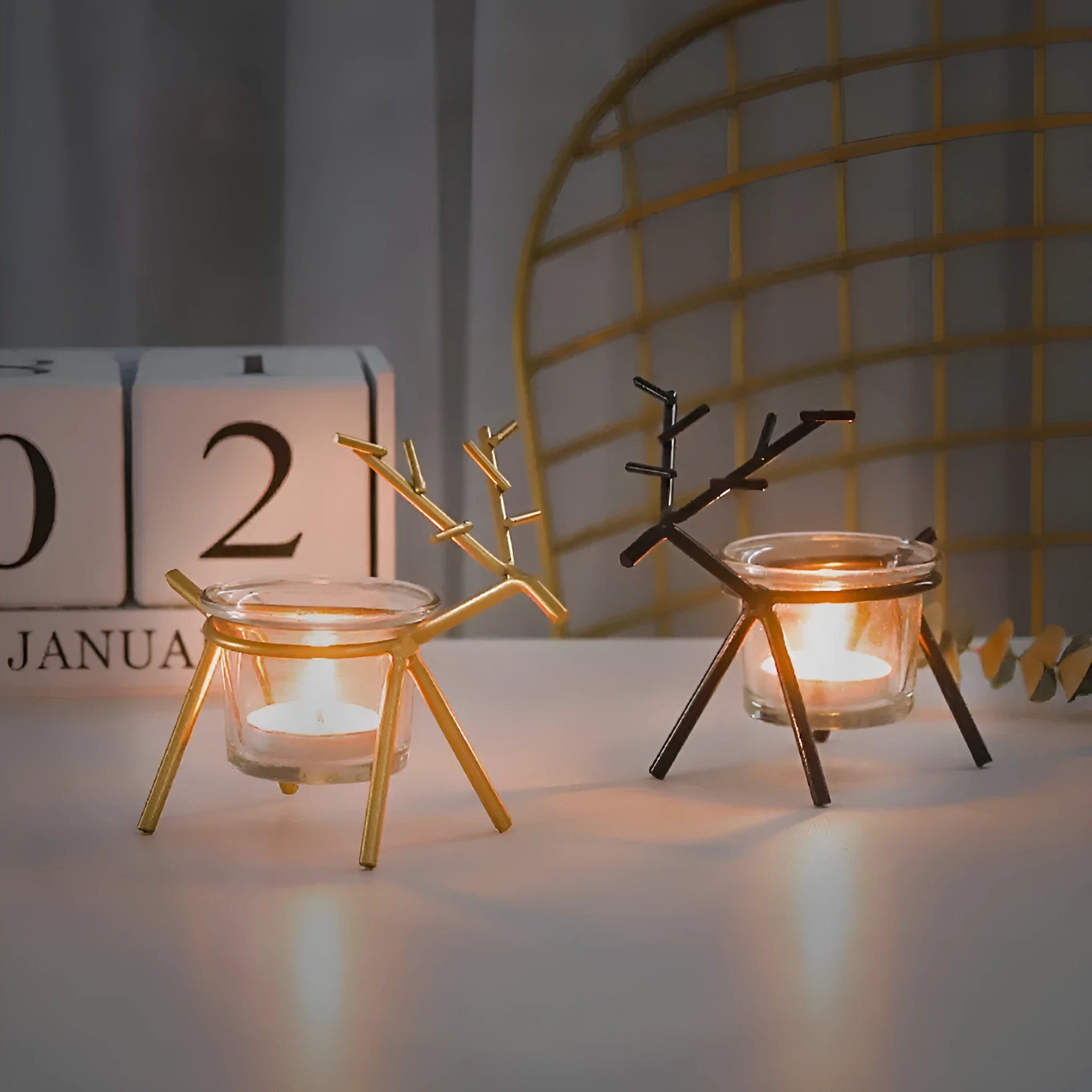 Wrought iron fawn candle holder with glass cup in gold electroplated finish on tabletop
