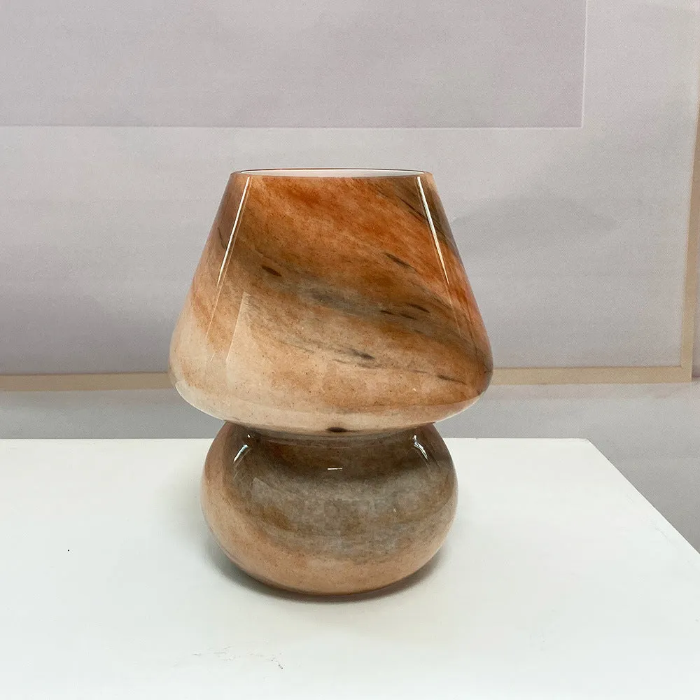 Handmade glass mushroom table lamp in Earth colour on a wooden bedside table with a soft glow