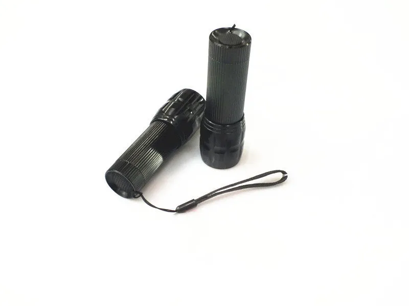 Black mini LED flashlight with telescopic head and tail push button switch on plain background