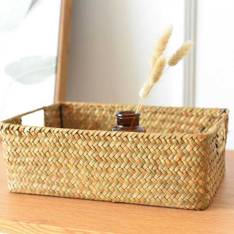 Handmade straw woven rectangular storage basket in natural grass fibre on a shelf